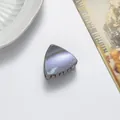 Macro detail of triangle cat ear hair clip with purple glitter finish on light surface - Khaki
