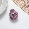 Detail of a mini round glitter hair claw clip with a shimmering metallic rose finish - Pink