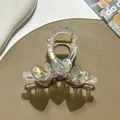 Macro detail of transparent hair claw with iridescent hearts and sparkling rhinestones - Gray