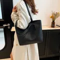Minimalist large black leather tote bag with shoulder straps shown on a model - Black