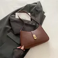 Minimalist dark brown leather shoulder bag with gold twist lock on grey blazer fabric - Brown