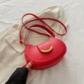Red vintage crescent saddle bag with gold hardware and adjustable strap on white suit - Red