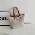 Minimalist beige canvas tote bag with brown leather handles and silver metal detail - Brown