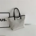Minimalist grey woven tote bag with black faux leather handles and silver metal detail - Black