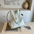 Bolso tote minimalista de nailon azul claro con cordón y correa de hombro en escena interior - Verde
