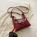 Elegante wijnrode lederen schoudertas met zilveren metalen strik en een slanke riem - Bordeauxrood