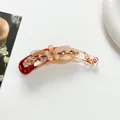 Große Acetat-Bananenklammer mit Blüten-Design und funkelndem Strassbesatz im Detail - Red + Champagne Gold