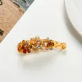 Detailed close-up of amber flower banana hair clip with sparkling rhinestones - Gold