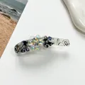 Détail macro d'une pince banane élégante avec fleurs en marbre bleu et perles cristal - Bleu foncé