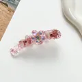 Vue détaillée de la pince banane rose avec fleurs en cristal et motifs papillons brillants - Rose