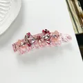 Macro detail of pink acetate banana clip with sparkling crystals and floral accents - Pink
