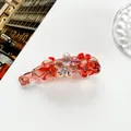 Détail macro d'une pince banane en résine rose ornée de fleurs en cristal - Rouge