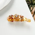 Close-up of amber banana hair clip with crystal flower beads on a white background - Gold
