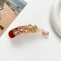 Detailaufnahme einer Blumen-Bananenspange mit rotem Acryl-Farbverlauf und Strasssteinen - 3D Blumen Stil / Champagnergold