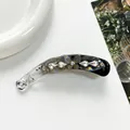 Dettaglio del fermaglio a banana con strass luccicanti e un motivo floreale perlato - Grigio
