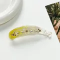 Detail view of a yellow gradient banana hair clip with rhinestones and a white flower - Yellow