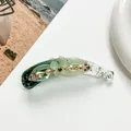 Detail shot of green acrylic banana clip with floral motifs and champagne rhinestones - Green