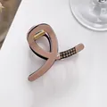 Detail of a milk tea resin hair claw with rhinestone accents and golden spring - Pink