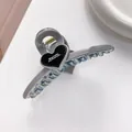 Detail of grey heart-shaped claw clip with 'Barrette La France' text and golden spring - Gray
