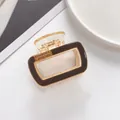 Détail d'une pince à cheveux rectangulaire marron foncé avec strass sur fond blanc - Café