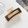 Detailed macro view of amber resin hair claw clip with rhinestones and gold spring - Coffee