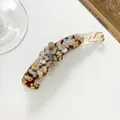 Detail view of tortoiseshell banana hair clip featuring floral patterns and rhinestones - Light Brown