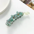 Dettaglio del fermaglio a banana con fiori glitterati verdi e strass ambra luminosi - Verde