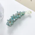 Detailaufnahme der blauen Glitzer-Blumen-Haarklammer mit bernsteinfarbenen Strasssteinen - Grün