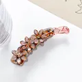 Makro-Detail der bernsteinfarbenen Bananenspange mit Glitzerblüten und kleinen Kristallen - Dunkelbraun