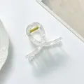 Detail einer transparenten Haarklammer aus Harz mit Karomuster und goldener Feder - Transparenter Cremefarbener Karo-Stil / Weiß