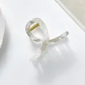 Nahaufnahme einer weiß marmorierten Haarklammer mit goldener Feder auf einem Teller - Halbdurchsichtiger Cremefarbener Marmorstil / Grau