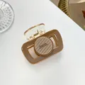 Detail der milchteebraunen runden Harz-Haarklammer mit Barrette La France-Schrift - Dunkelbeige