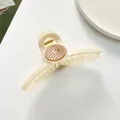 Detail of 11cm cream shark hair claw with round brown accent and gold spring - Off White