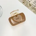 Details einer braunen transparenten Haarklammer mit gestreiftem Herz und Schriftzug - Dunkelbeige