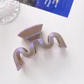 Macro shot of wavy hair claw clip with shimmering purple glitter and S-shaped design - Khaki