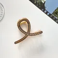Détail d'une pince à cheveux dorée champagne avec touches marron et cinq strass brillants - Café