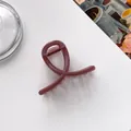 Close-up of burgundy matte glitter hair claw clip with crossed twist design on white background - Pink