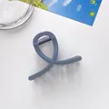 Close-up of a dark grey-blue glitter hair claw clip with cross-twist design on a desk - Gray