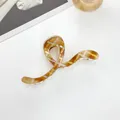 Detail view of 13cm tortoiseshell hair claw clip with S-curve design and glossy finish - Large Geometric Style / Gold