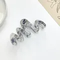 Close-up of wavy acetate hair claw clip with grey marble texture and metal spring - Ink