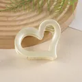 Dettaglio della pinza per capelli a cuore crema con finitura opaca su base in legno - Bianco Sporco