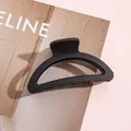 Gros plan sur une pince à cheveux noire mate évidée sur un fond minimaliste chic - Noir