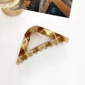 Macro detail of amber checkered triangle hair claw clip with transparent teeth - Gold