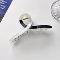 Detail of a large black and white marble hair claw clip with a gold metal spring - 11cm / Black