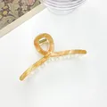 Top view of large amber marble pattern hair claw clip on white surface with decor - Light Amber Texture