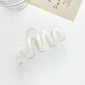 Detail shot of transparent wavy hair claw clip made of acrylic on a minimalist background - White