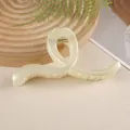 Detail of a large cream-colored hair claw clip with twisted geometric resin design - Off White