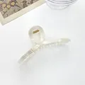 Detail view of a creamy marble pattern hair claw clip with golden metal spring and acrylic finish - Creamy Champagne