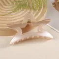 Detailed close-up of a large beige star hair claw clip on a natural wooden tray - Khaki