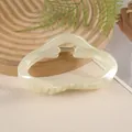 Close-up of 11cm cream cloud hair claw clip with golden spring on wooden tray - Off White